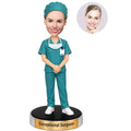 Custom female surgeon bobblehead in teal surgical scrubs with surgical cap, mask and ID badge