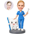 Custom female dentist bobblehead in blue scrubs standing beside a giant tooth and toothbrush