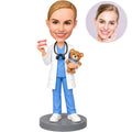 Custom female pediatric dentist bobblehead holding a dental model and teddy bear